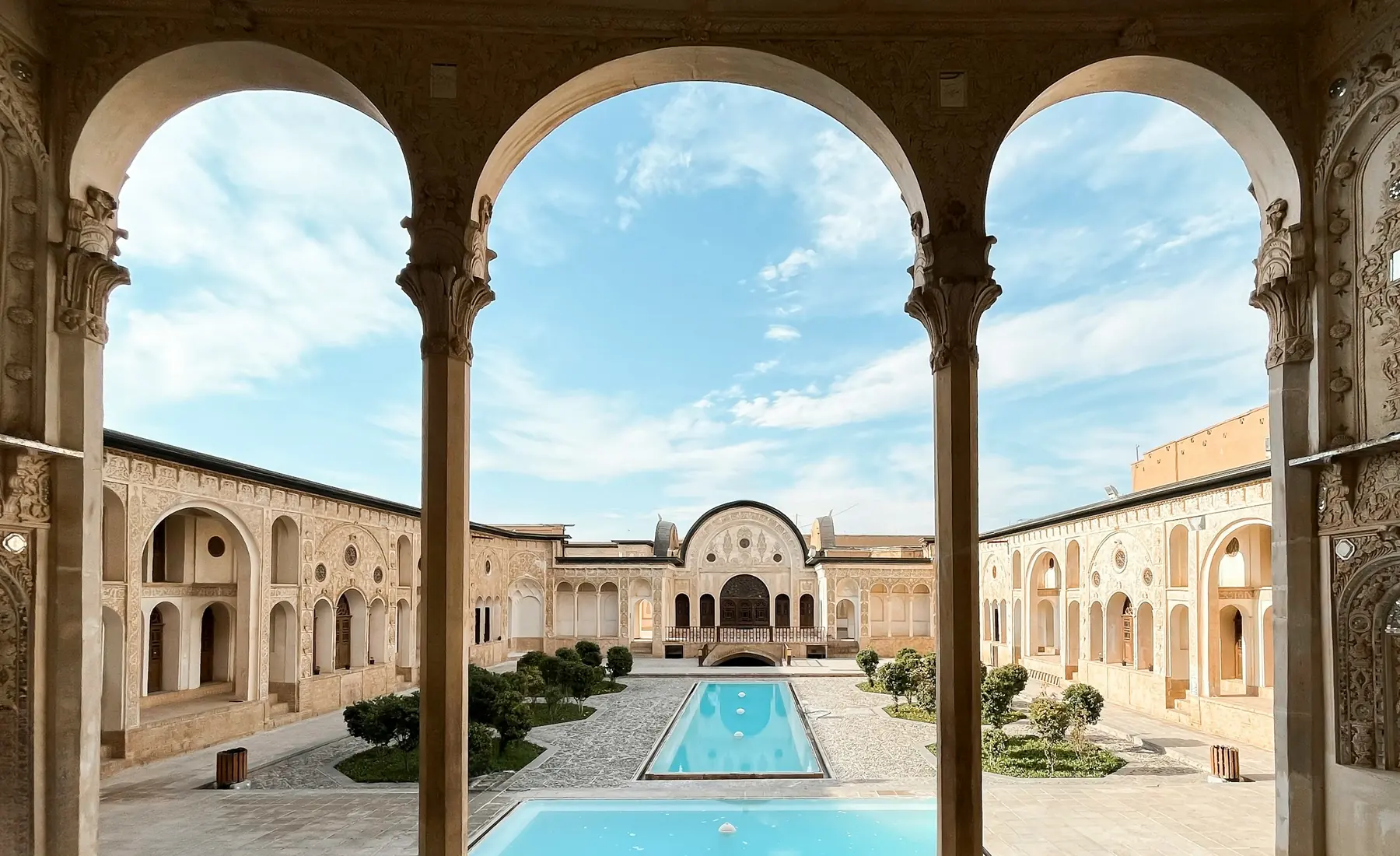 Arched windows looking over a courtyard and a long blue pool