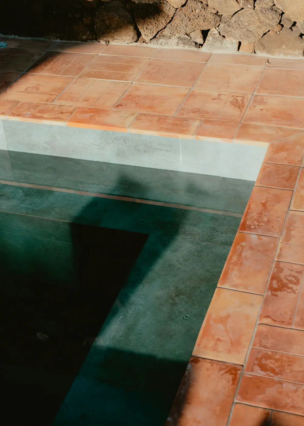 Terracotta tiles around a dark green plunge pool